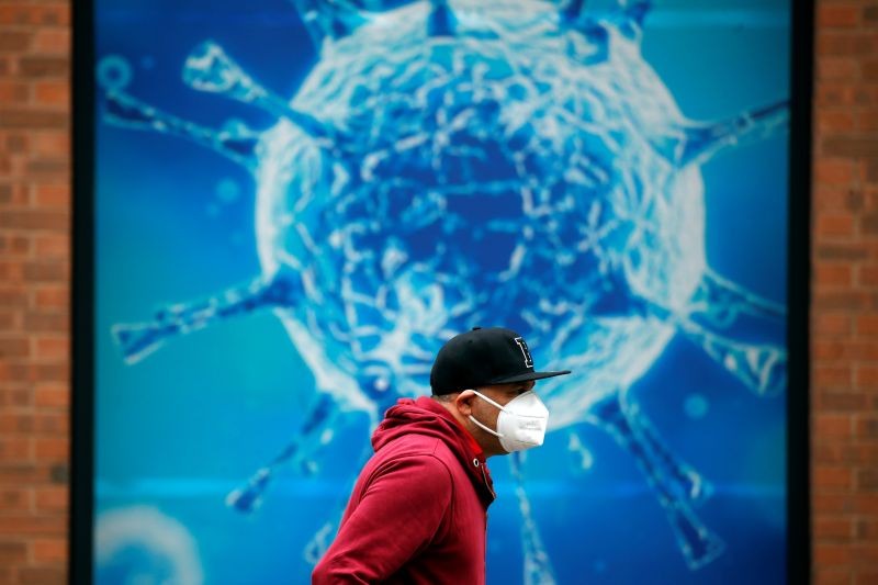 A man wearing a protective face mask walks past an illustration of a virus outside a regional science centre, as the city and surrounding areas face local restrictions in an effort to avoid a local lockdown being forced upon the region, amid the coronavirus disease (COVID-19) outbreak, in Oldham, Britain on August 3, 2020. (REUTERS Photo)